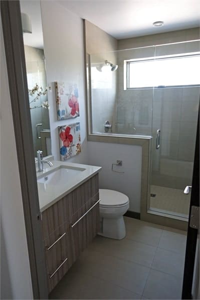 浴室里有漂浮的梳妆台、一间厕所和一间用无框玻璃板围起来的步入式淋浴间。