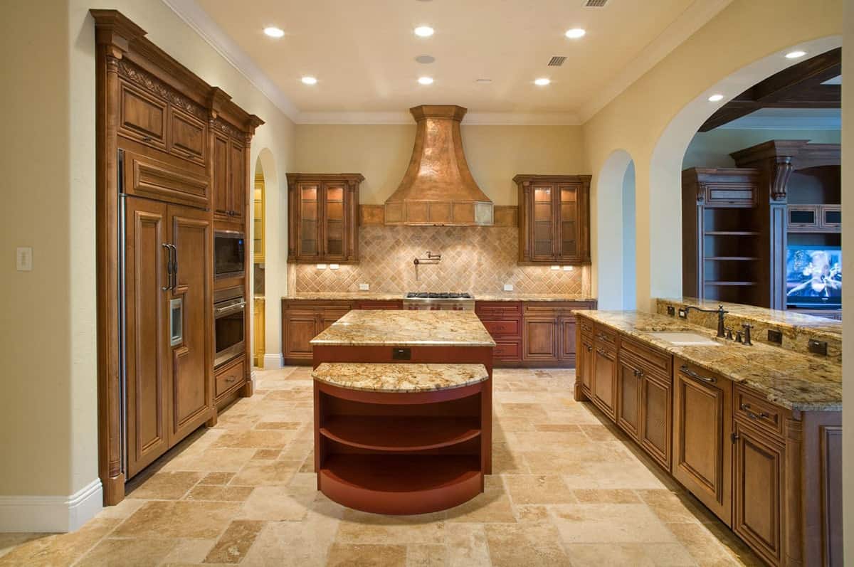 厨房有黄色墙壁，石灰石地板，木制橱柜和花岗岩台面。