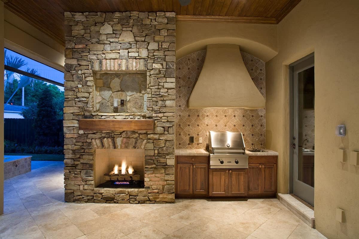 带顶棚的露台带有一间夏季厨房和一座石砌壁炉，壁炉旁有一个质朴的壁炉架。