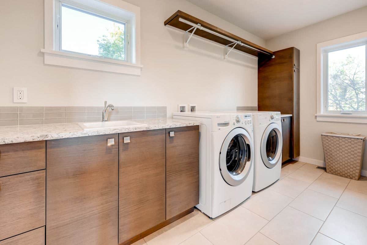 洗衣房配有白色前置电器、木制橱柜和陶瓷水槽。