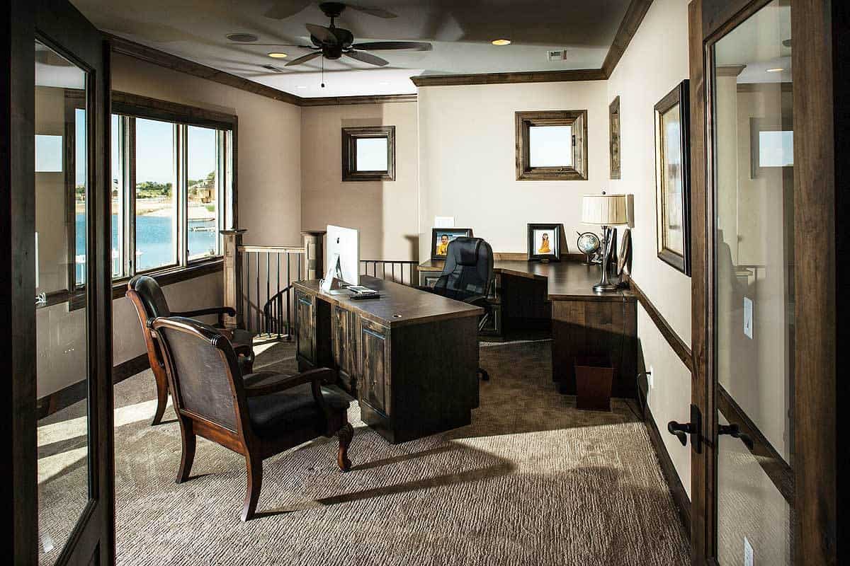 家庭办公室，深色的木头桌子和皮革椅子在地毯地板上。