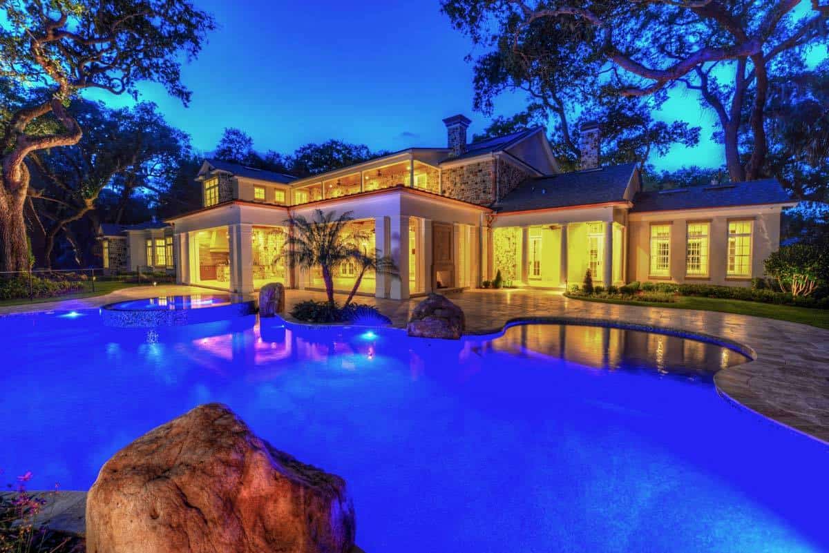 夜晚，房子的后视图显示了令人惊叹的泳池灯，与房子舒适的环境照明形成对比。