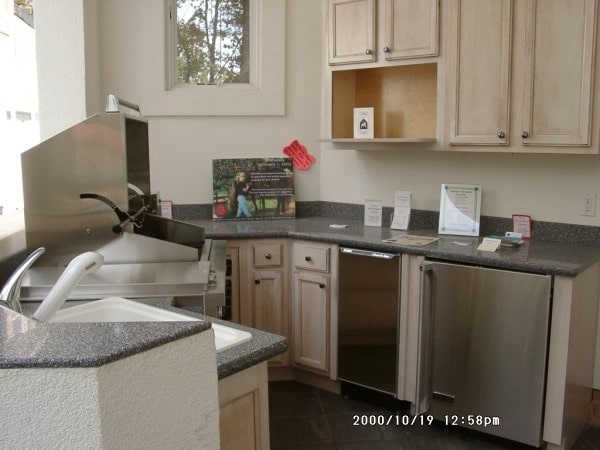 夏季厨房配备了不锈钢用具，黑色花岗岩台面，轻木橱柜，和一个两层半岛。