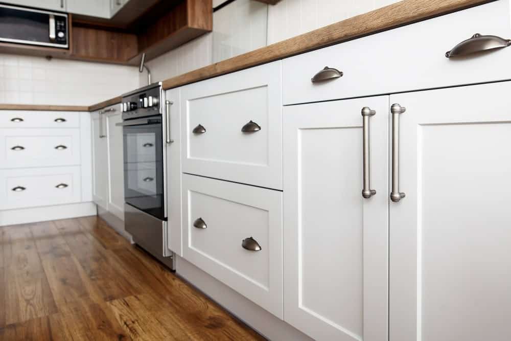 这是一个近距离观察厨房的白色摇床柜与钢把手相匹配的烤箱。