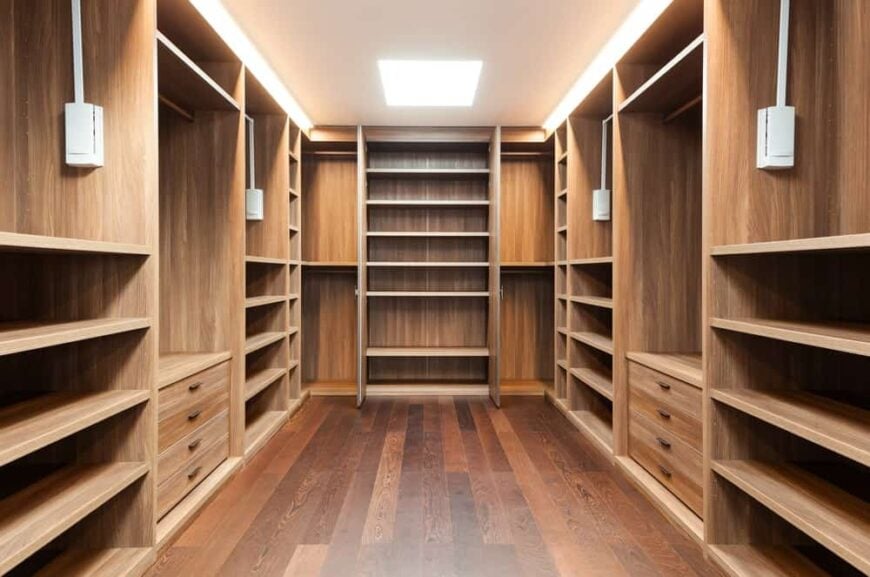 这是一个宽敞的步入式衣柜，硬木地板搭配衬砌墙壁的棕色木制橱柜。