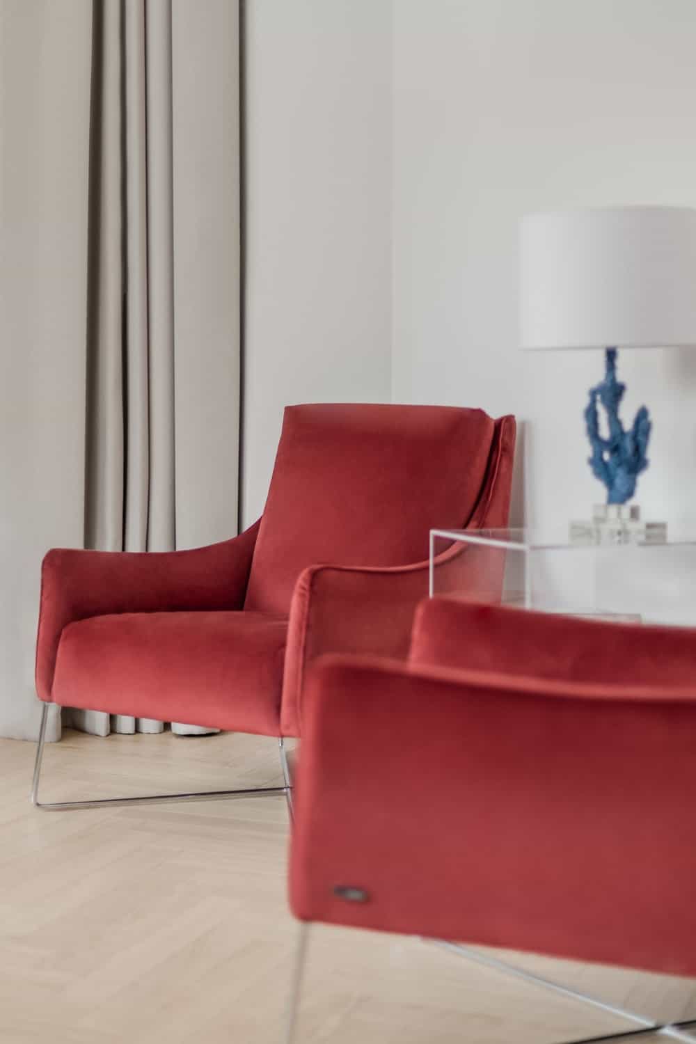 这两把软垫椅子有红色天鹅绒的美感，与墙壁和地板的浅色色调形成鲜明对比。