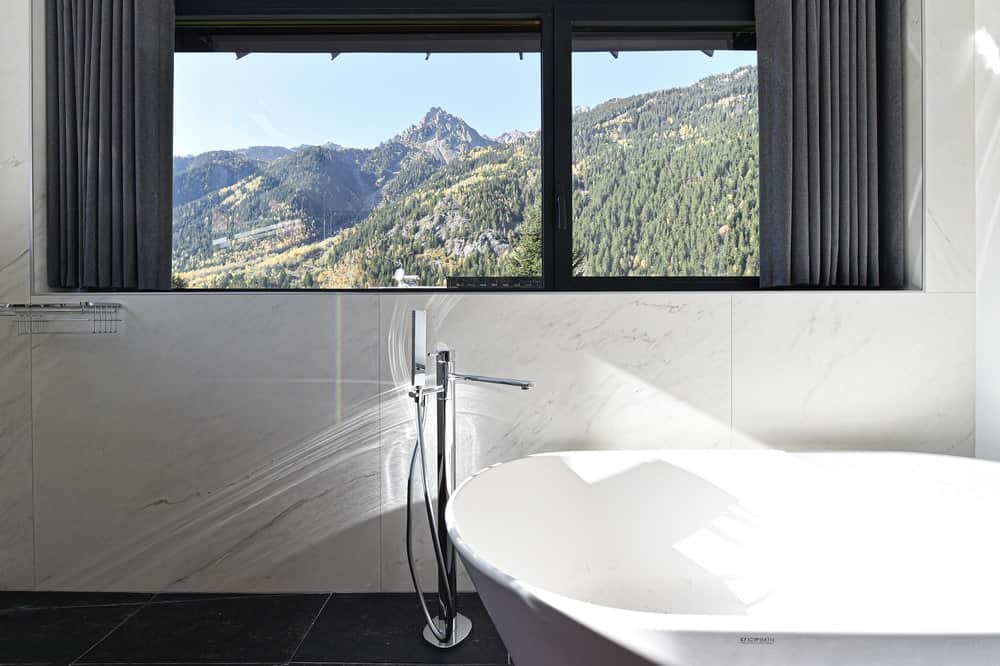 这是一个大型独立浴缸，顶部有一个大窗户，可以看到山景。