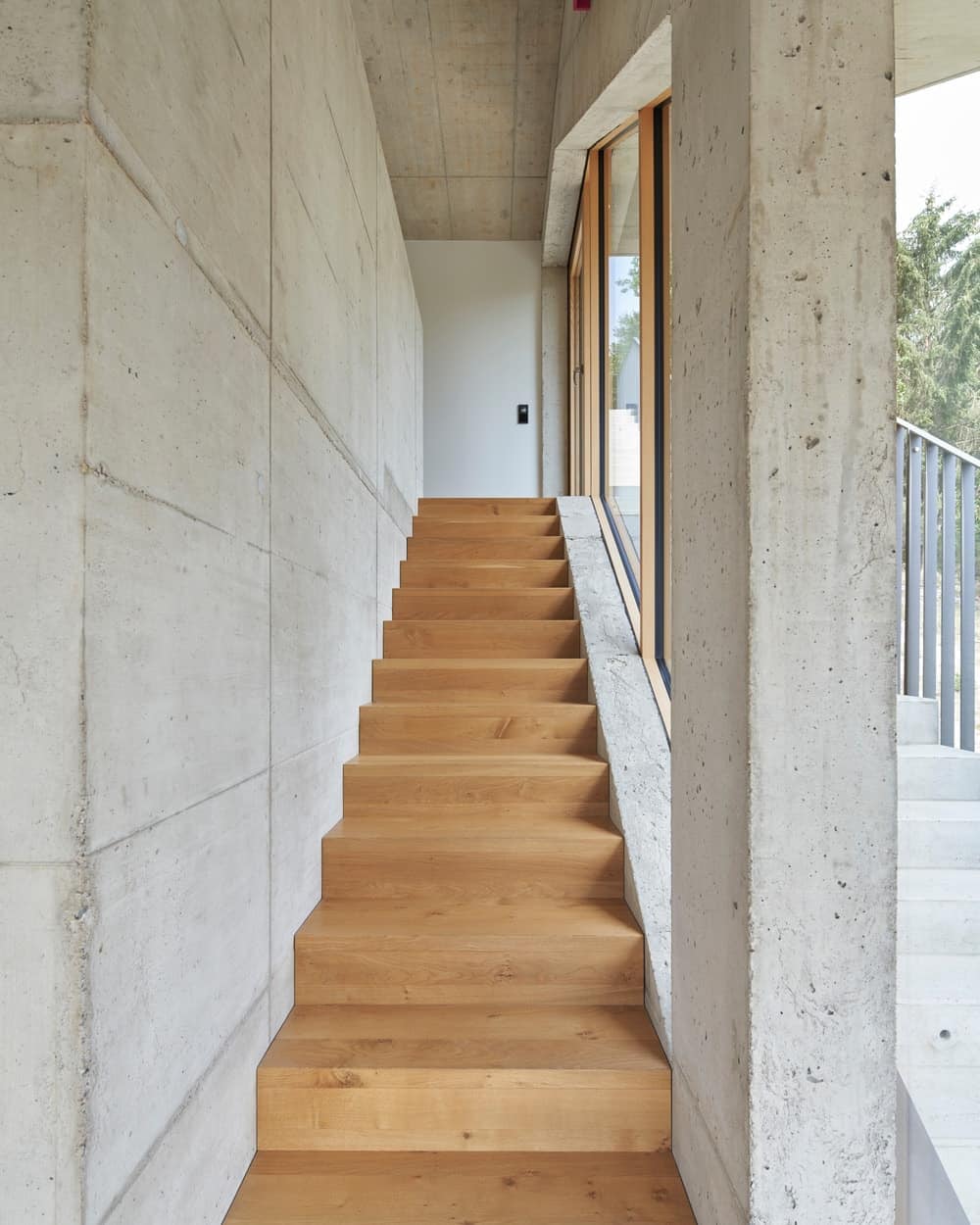这是室内楼梯的景观，楼梯的木质调阶与硬木地板相匹配，并被玻璃墙照亮。