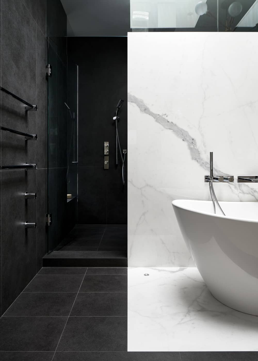 这是浴缸墙后面的步入式淋浴区，墙壁和地板上都贴着深灰色的瓷砖。