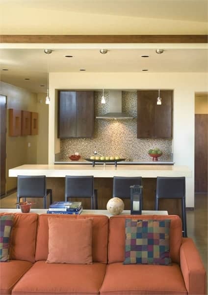 厨房位于橙色组合家具的后面。它有一个大岛台和石英台面，后挡板有马赛克瓷砖。