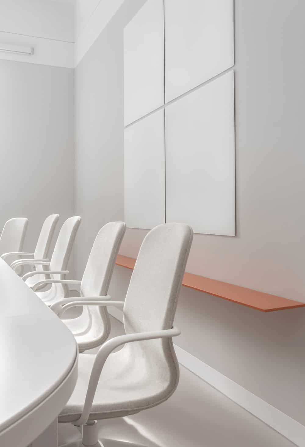 在会议桌的另一侧是一个漂浮的橙色架子，上面有一套墙壁装饰。
