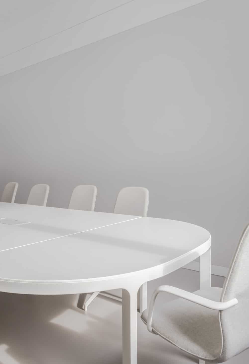 这是现代会议桌的近景，它与白色办公椅、白色墙壁和白色天花板完美搭配。