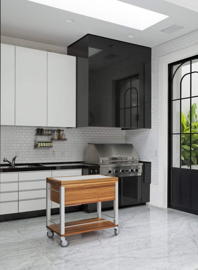 厨房的光滑和现代的黑白橱柜使不锈钢元素与木制厨房岛一起脱颖而出。