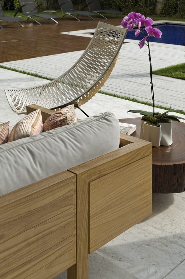 这是一个近距离观察室外的木制沙发，装饰着一个木制的边桌和编织柳条椅。