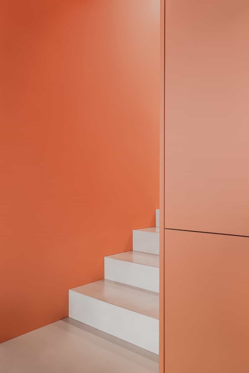 这是浅灰色楼梯台阶，与哑光橙色墙板形成对比。