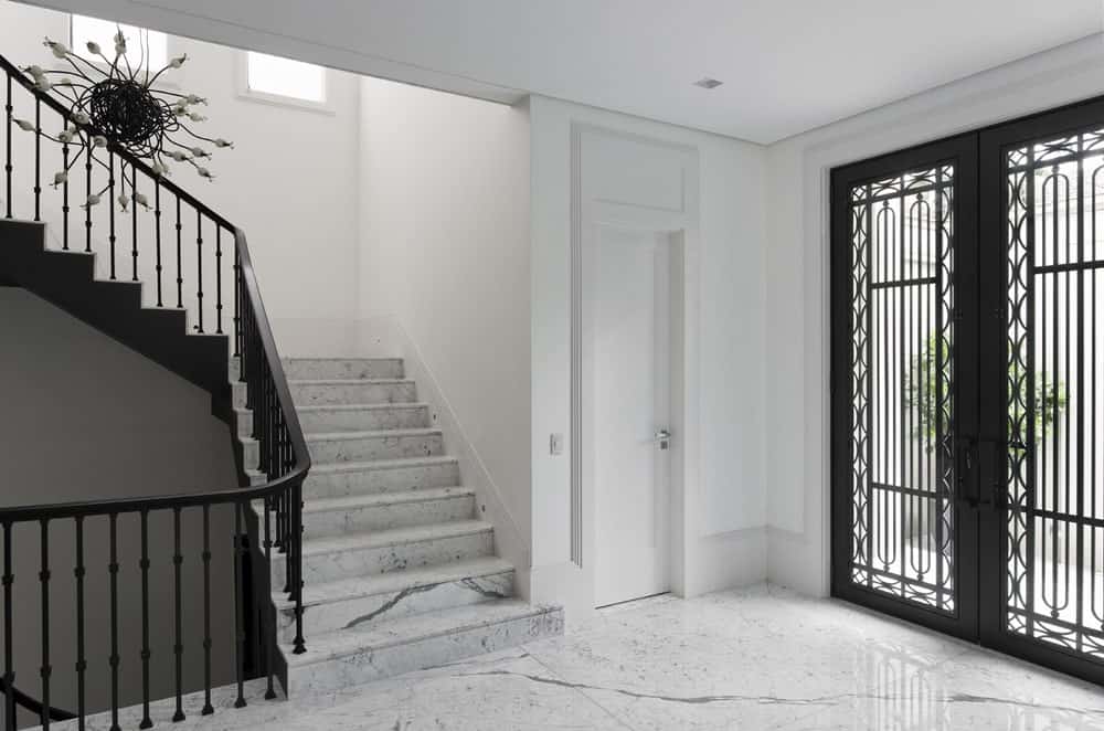 一进入房子，你就会受到这个门厅的欢迎，白色大理石元素与黑色锻铁栏杆和门框形成对比。