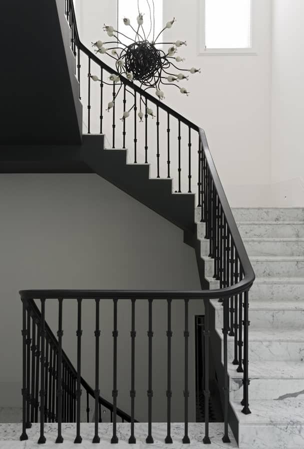 这是一个近距离观察黑白色调的楼梯，黑色锻铁栏杆在白色墙壁的衬托下突出。