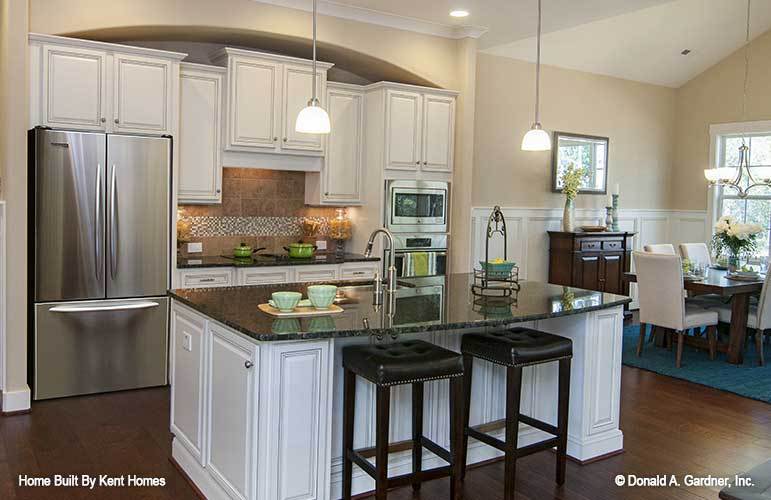 厨房配有白色橱柜，不锈钢电器和花岗岩顶部岛台。