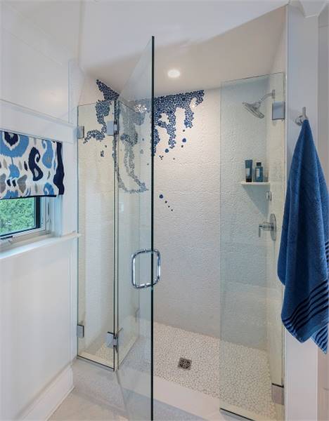 步入式淋浴间有白色墙壁、镀铬固定装置、浮动搁板和一扇玻璃铰链门。