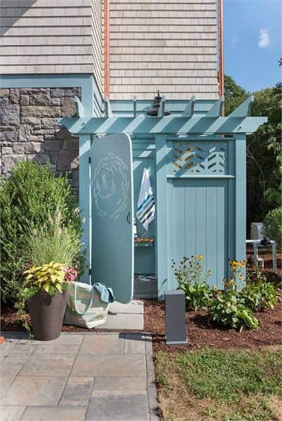 一间室外淋浴房，蓝色木墙和一扇门连着车库。