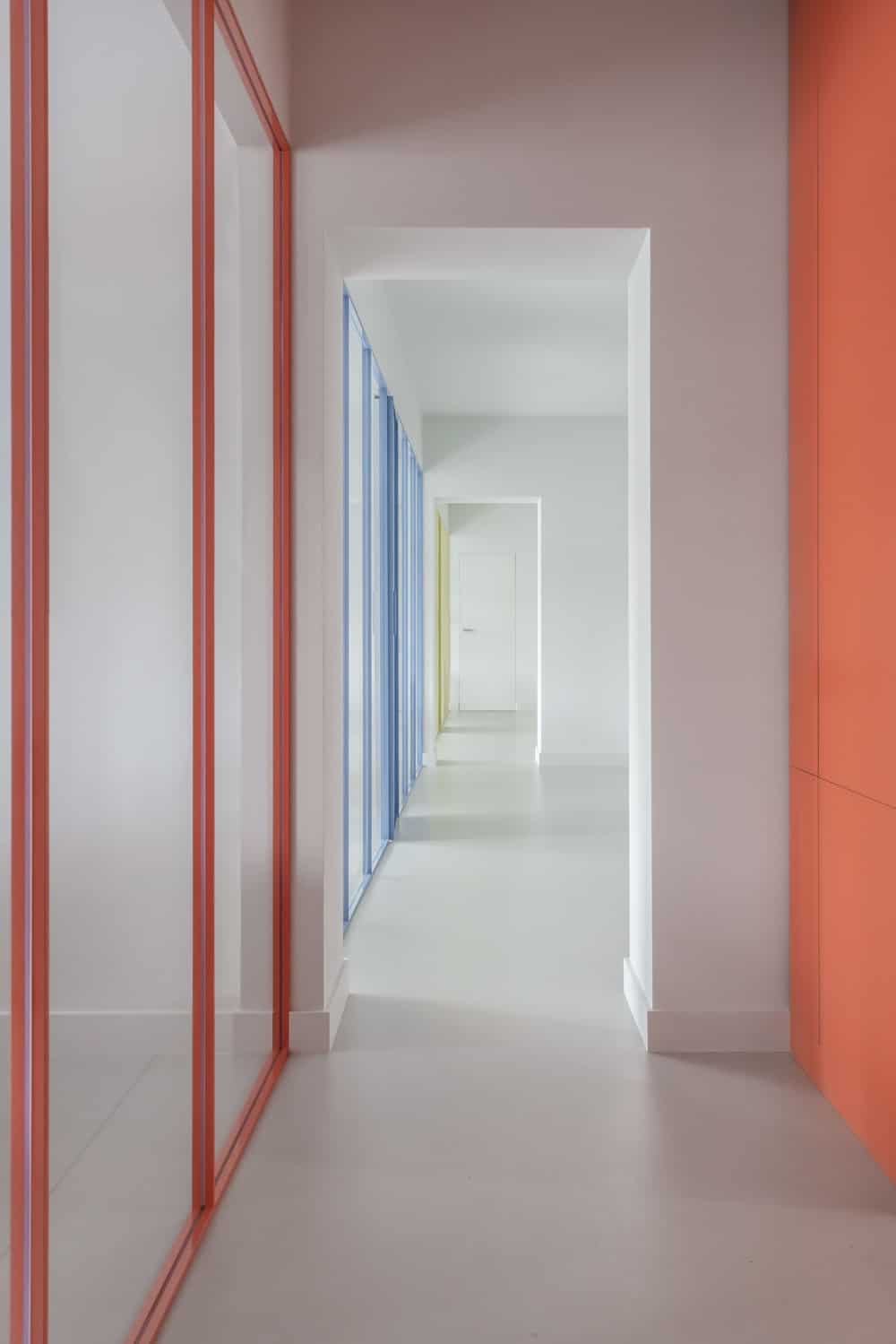 这是一个有一面玻璃墙的走廊，有彩色的框架，在明亮的色调中脱颖而出。