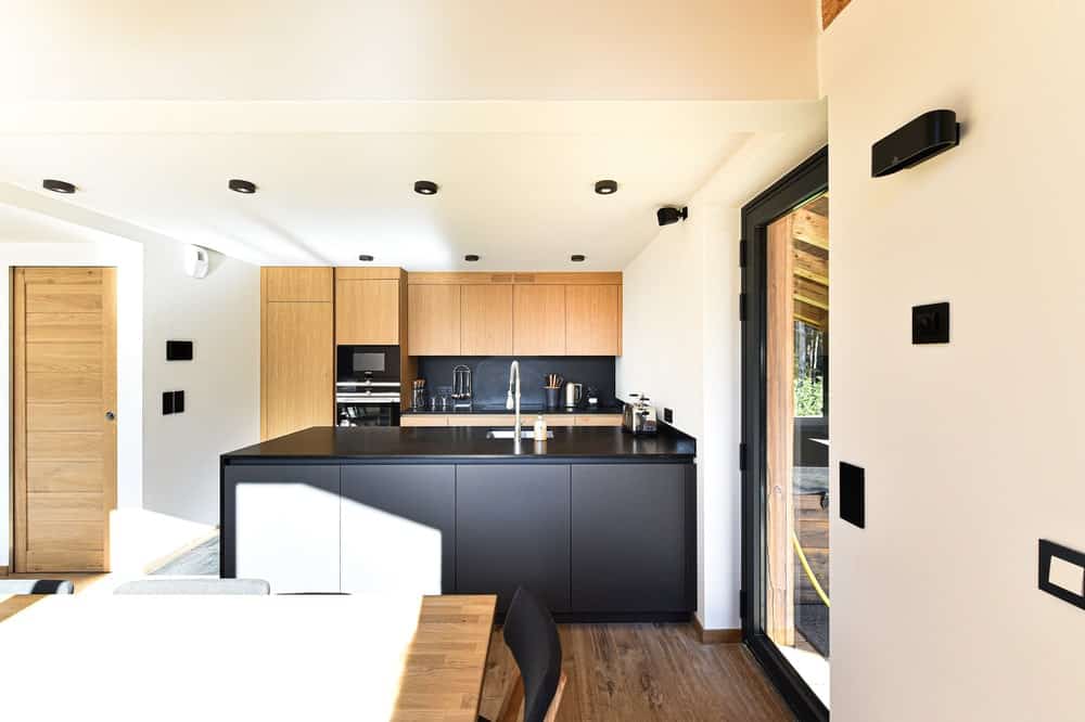 这是一个现代而简单的厨房，一个黑色的厨房半岛，在白色的墙壁和天花板上脱颖而出。