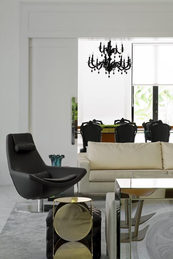 从客厅的近景来看，米色沙发一侧的黑色皮革转椅正对着玻璃咖啡桌。