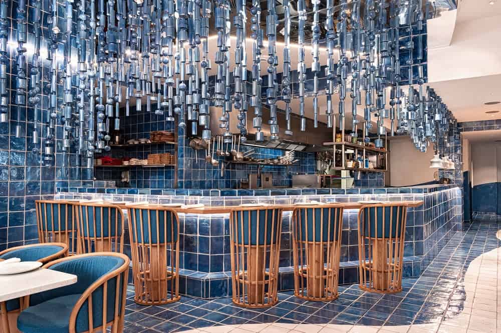 这是一个大酒吧的近距离观察，它与木制凳子搭配，蓝色垫子与主题搭配。
