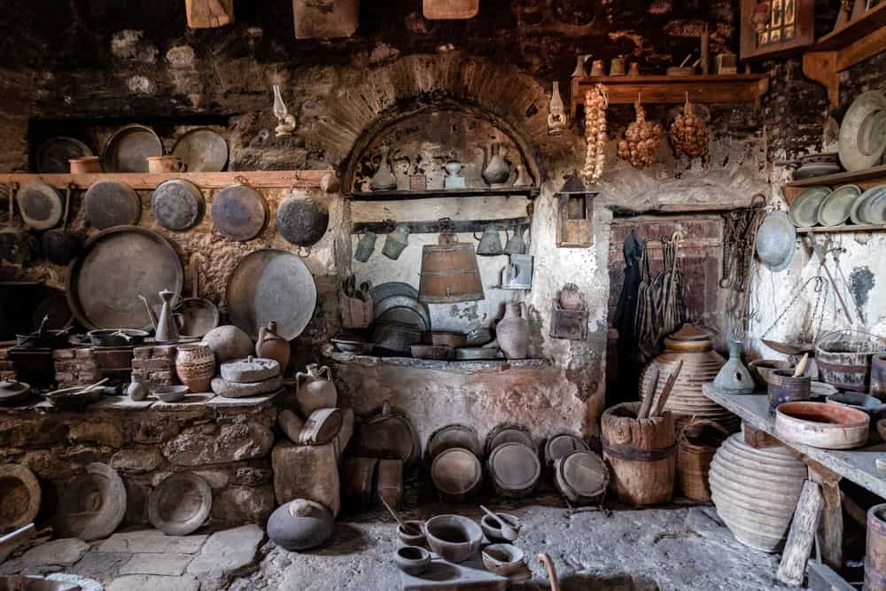 一个质朴而古老的厨房，锅和炊具挂在墙上。