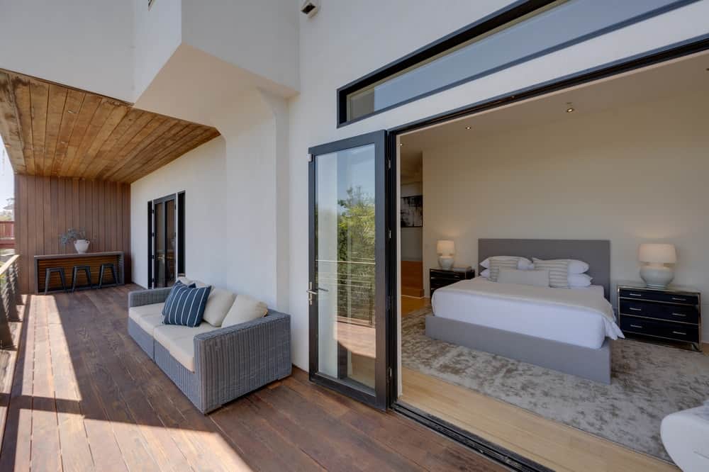 几步从卧室阳台的木甲板是舒适的家具和明亮的白色墙壁。图片由Toptenrealestatedeals.com。