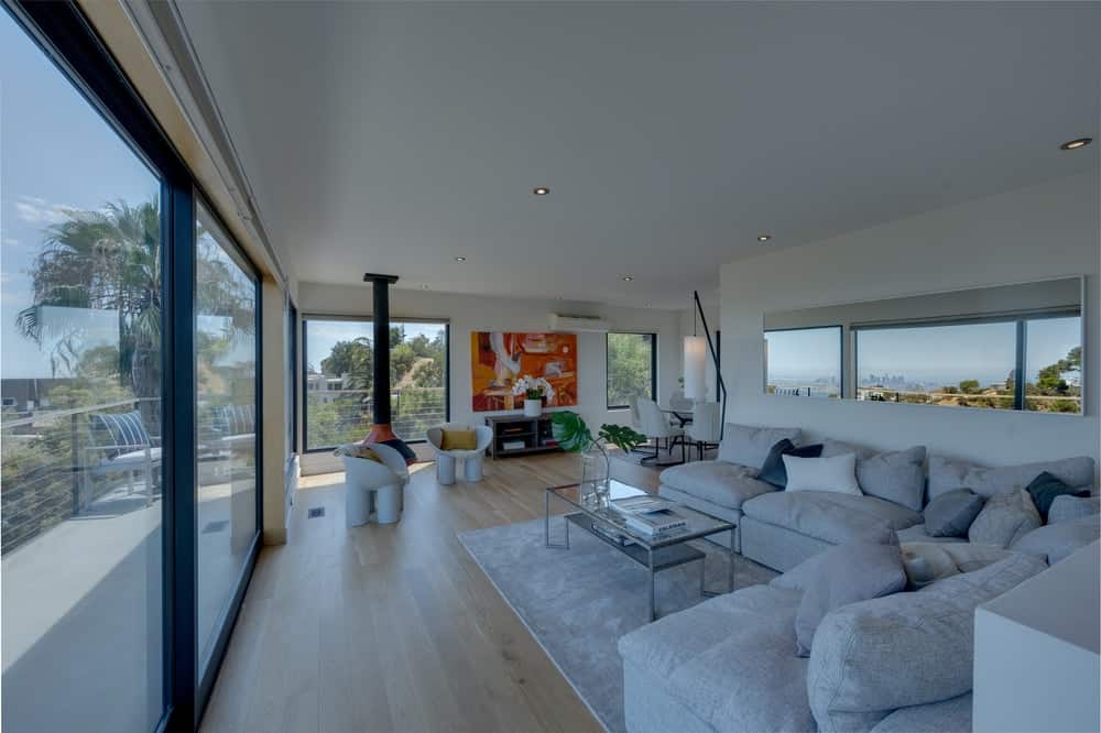 这是家庭大房间和一个大的房间面积l形截面沙发搭配玻璃咖啡桌。图片由Toptenrealestatedeals.com。