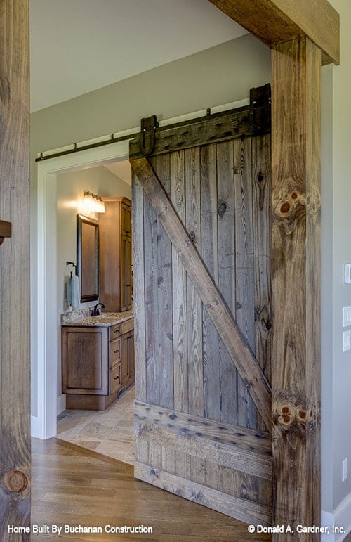 一扇带有滑动谷仓门的敞开门通往主浴室。