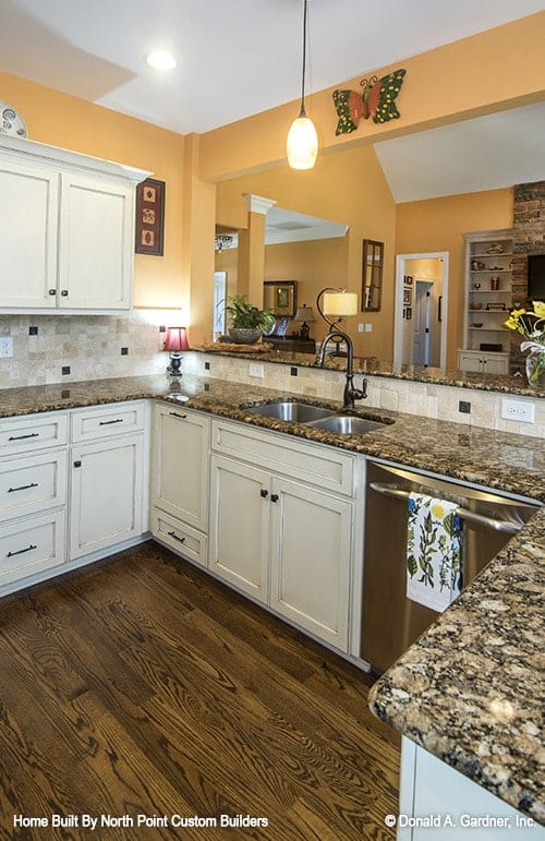 厨房配有白色橱柜、双碗水槽、花岗岩台面和大理石马赛克后挡板。