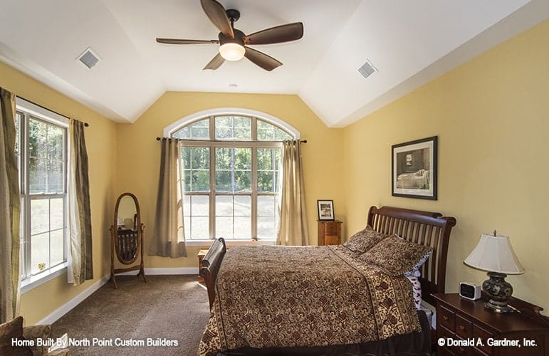 主卧室里有木制家具、大窗户、地毯地板和凹形天花板。