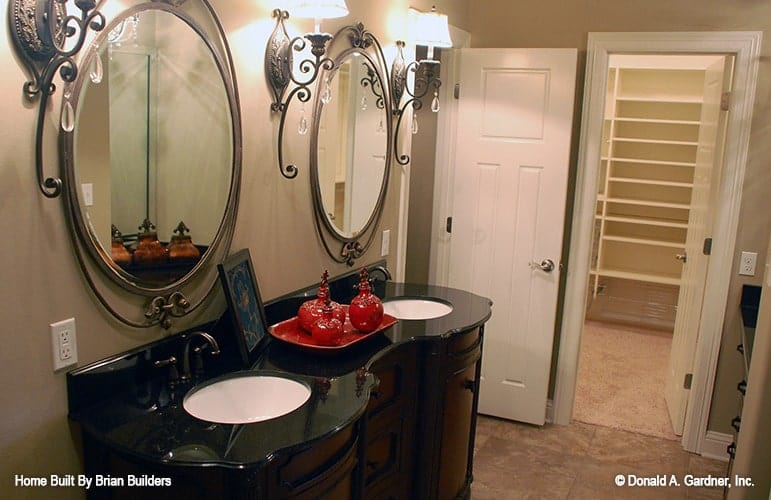 主浴室设有双水槽梳妆台，搭配复杂的椭圆形镜子。
