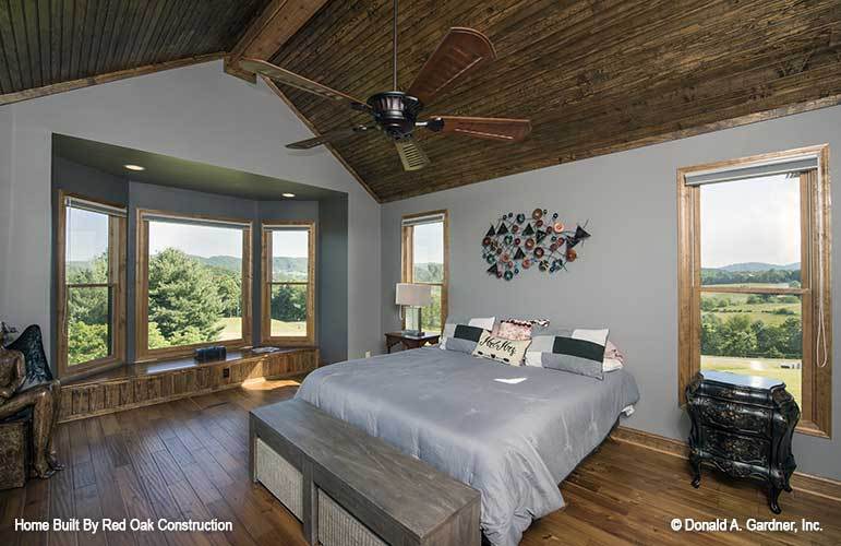 主卧室有一张舒适的床，木制床头柜，天花板上挂着一个吊扇。