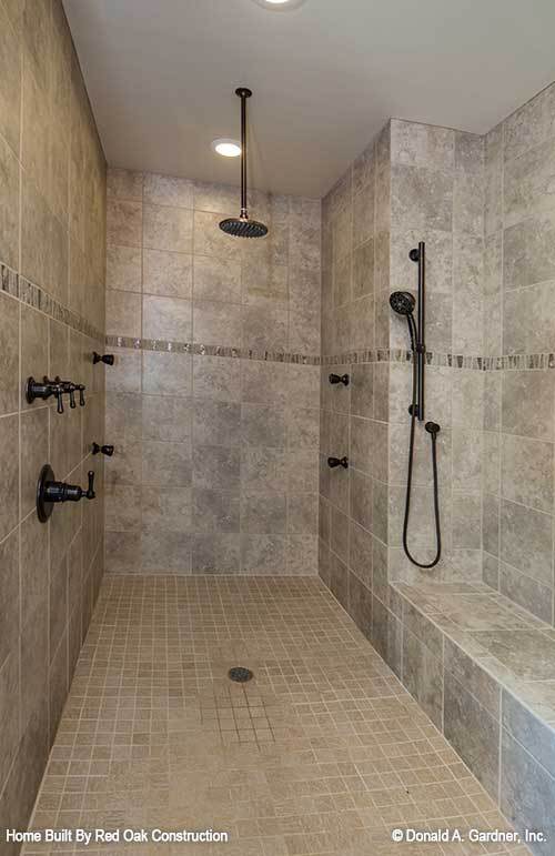 步入式淋浴间配有锻铁设备、大理石瓷砖墙壁和一个内置座椅。