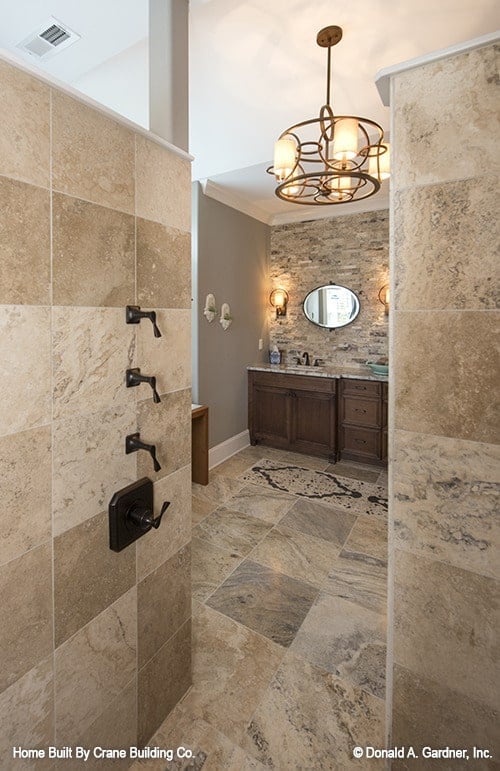 步入式淋浴间配有锻铁固定装置和与浴室地板相配的瓷砖墙壁。