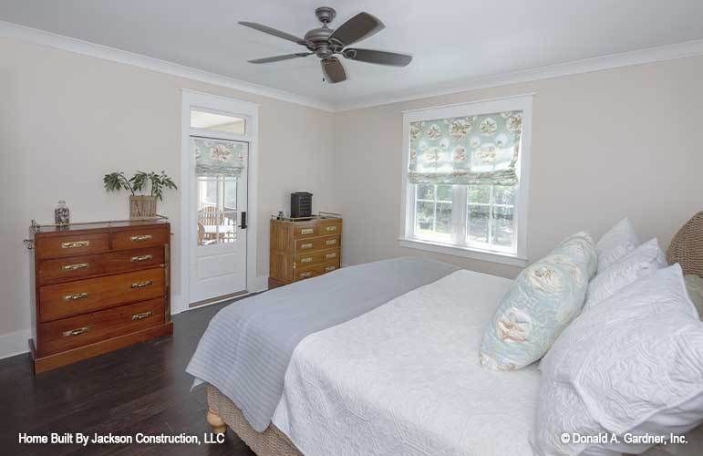 主卧室有木制家具，奶油色墙壁，深色硬木地板，普通的白色天花板上装有风扇。