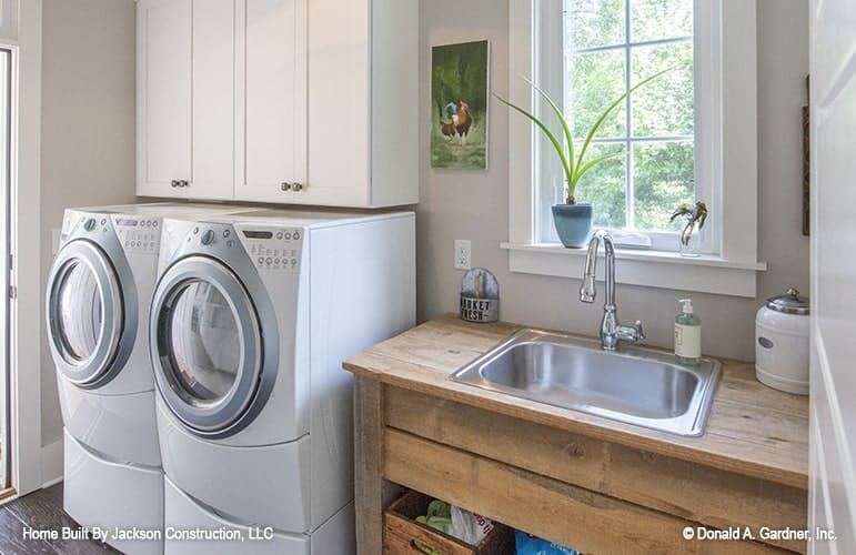 杂物间与前负荷电器，白色橱柜，和一个洗手台放置在窗户下。杂物间与前负荷电器，白色橱柜，和一个洗手台放置在窗户下。