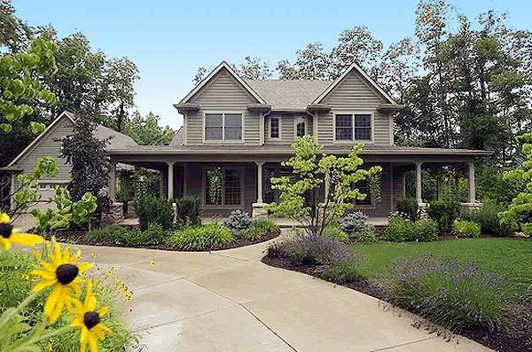 一个充满绿色植物的美丽庭院用灰色壁板和锥形柱子装饰着住宅的立面。