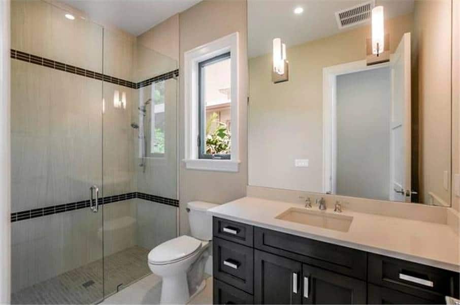 浴室有步入式淋浴，厕所，洗手台梳妆台和无框镜子。
