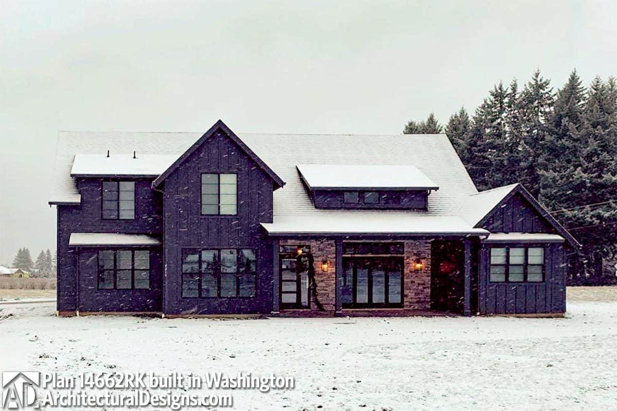 房屋的深色外观与砖突出在雪地上。