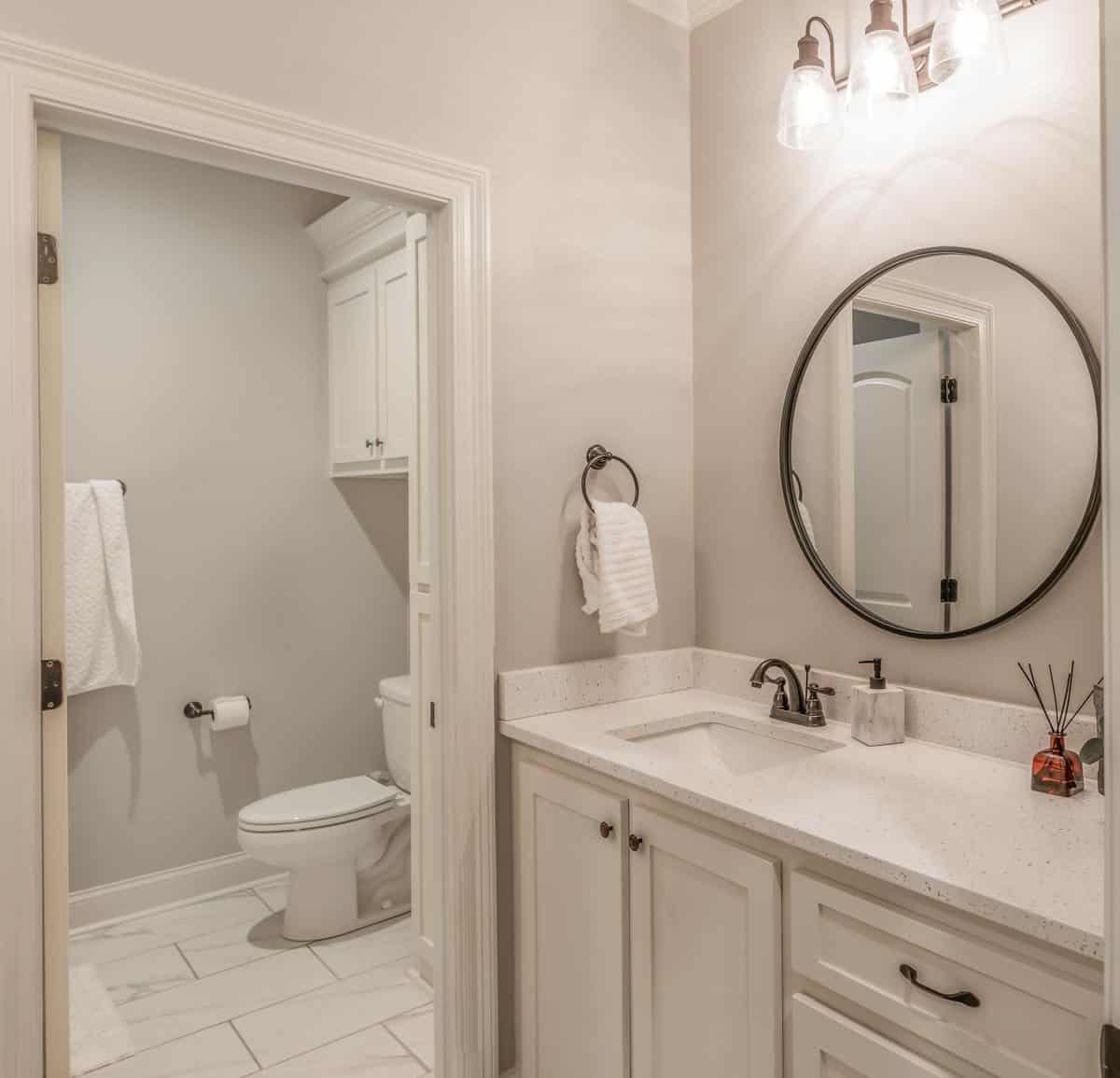 这间浴室有一个白色的梳妆台和一间铺着大理石瓷砖地板的卫生间。