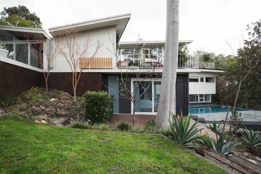 这是一个外观的这所房子，带后院游泳池，阳台和蝴蝶屋顶。