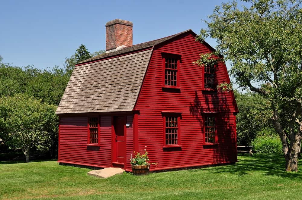 一个山寨式的家，黑色的红色外墙，砖烟囱和曲柄屋顶。