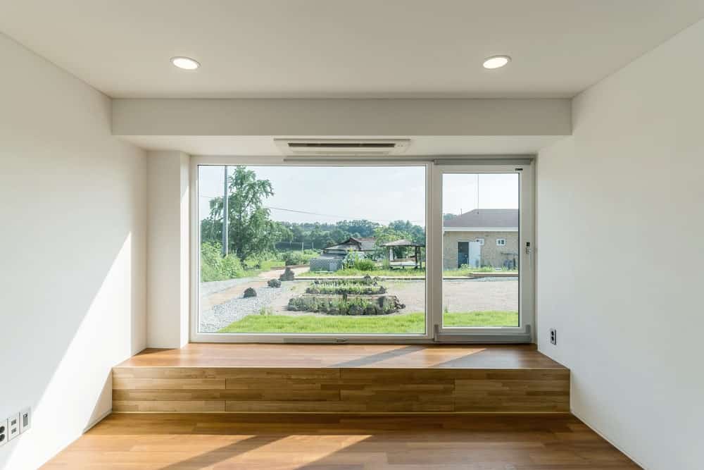 这是客厅区，有硬木地板，白墙和一堵大玻璃墙，可以看到外面的风景。
