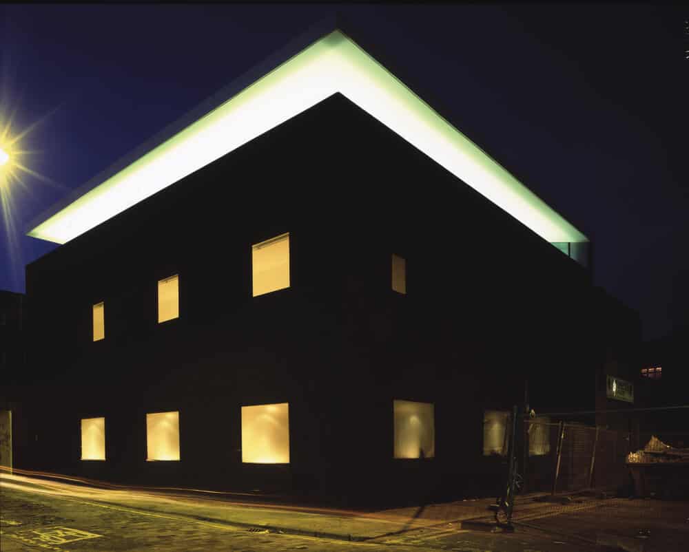这是房子的夜景，展示了窗户和顶楼玻璃墙的温暖光芒，给房子一个独特的外观。