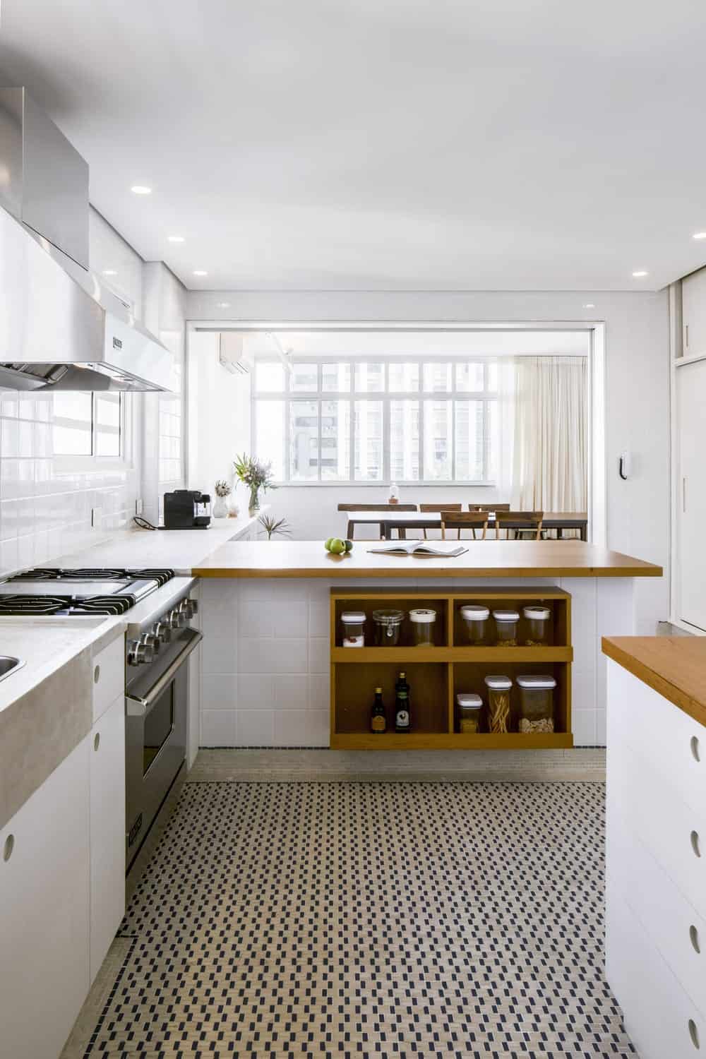 这是厨房半岛的另一侧，内置的架子与木质台面的色调相匹配，并辅以明亮的白色色调。