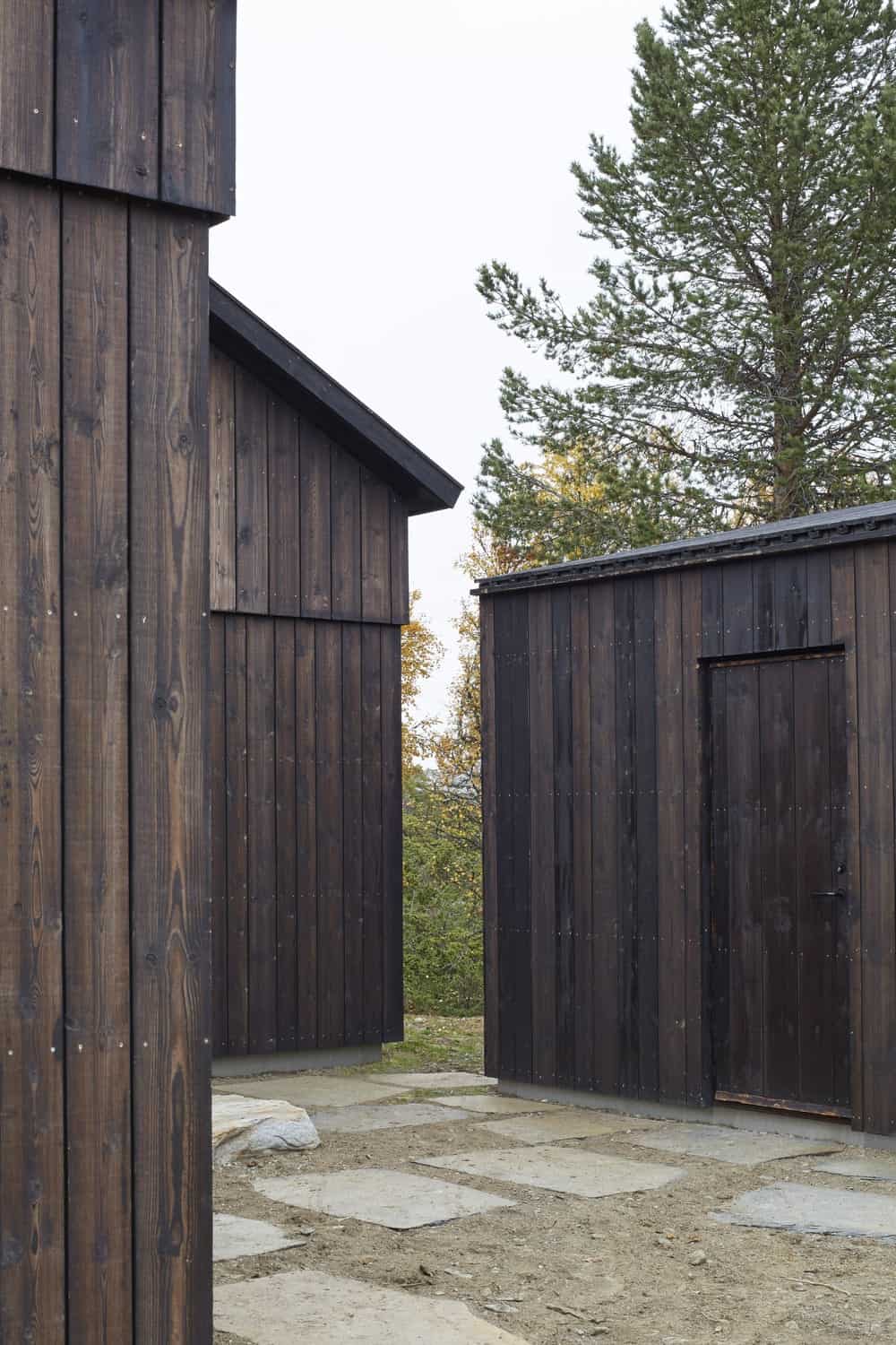 房子的结构与其深色的木质色调和设计以及与墙壁融为一体的门保持一致。